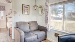 A living room with a gray sectional sofa, a large window with a view, a ceiling fan, and a framed picture on the wall. - T06 - Dory @ Trollers Lodge (Depoe Bay)