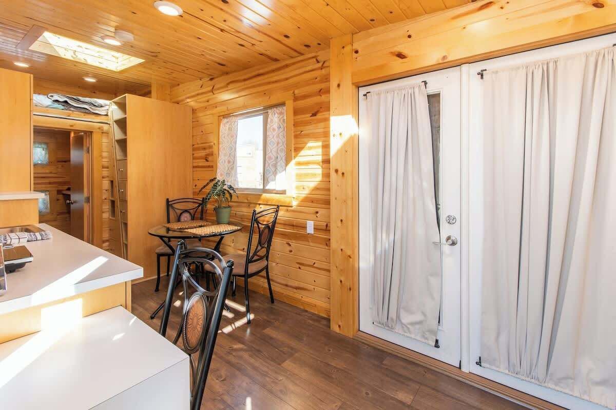 A wooden cabin interior with a dining area, a small table, and chairs.