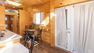 A wooden cabin interior with a dining area, a small table, and chairs.
