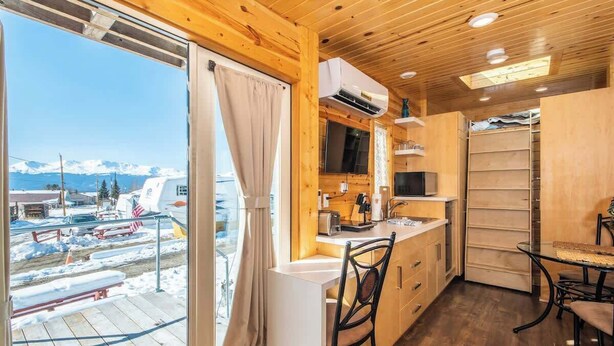 Una cocina moderna con un ventanal grande, interior de madera y vistas a un paisaje nevado.