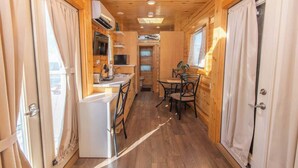 Un interior estrecho de madera con kitchenette, comedor y un baño pequeño.