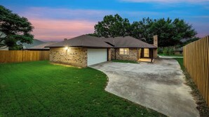 Une maison d’habitation avec un garage, une pelouse bien entretenue et une allée menant au garage.