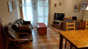 A living room with a sofa, a wooden table, a TV, and a cabinet. - Ground floor apartment Gerbera (Zinnowitz)