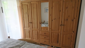 A bedroom with a bed, wooden wardrobe, and a mirror. - Ground floor apartment Gerbera (Zinnowitz)