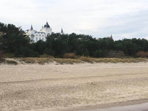 Une plage avec un grand bâtiment blanc en arrière-plan.