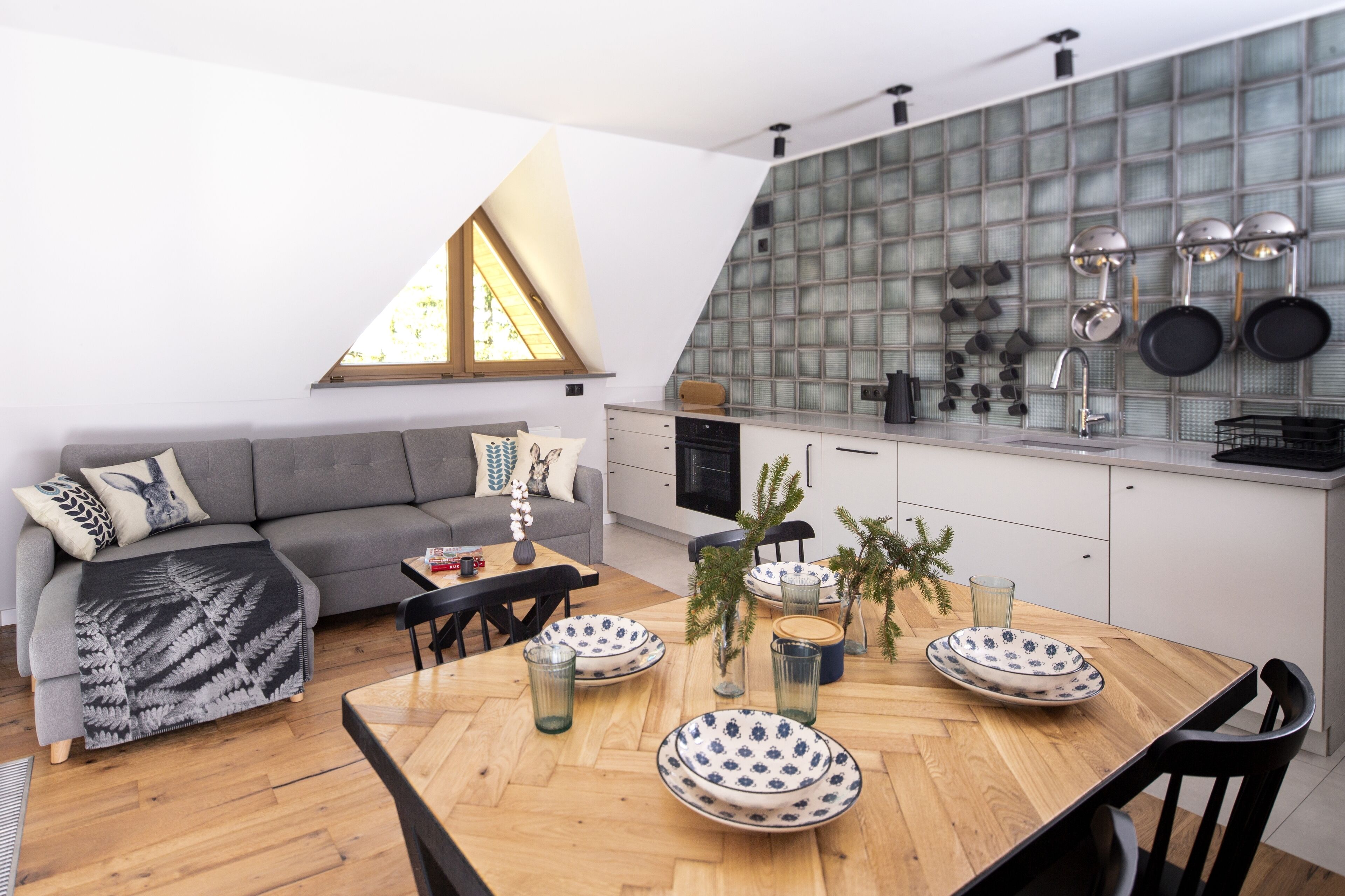 Eine moderne Küche mit Essbereich, mit einem Holztisch, gedeckten Tellern, Gläsern und einer Pflanzvase.