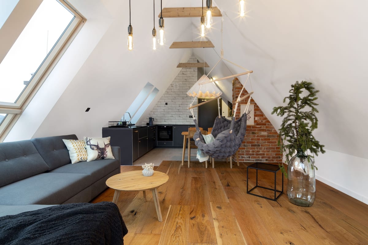 A loft-style living space with a sloped ceiling, exposed brick, and a modern kitchen.
