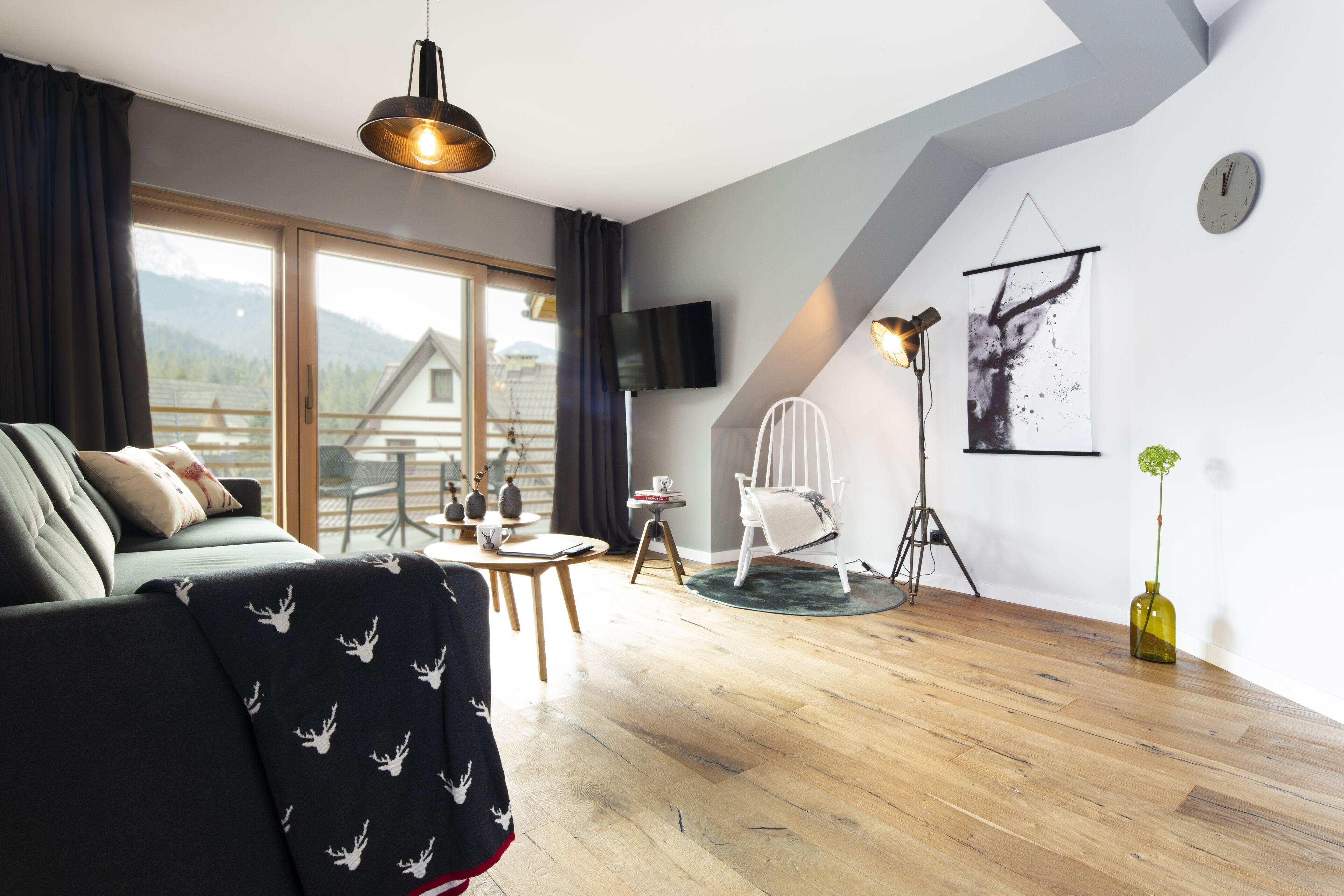 Una sala de estar moderna con un sofá, una mesa de comedor y un televisor montado en la pared.