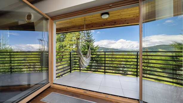 A balcony with a hammock, wooden floor, and a view of green hills and a clear sky. - Green Deer Premium (Zakopane)