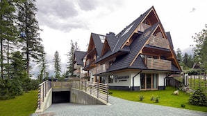 A modern chalet with a steeply pitched roof, wooden balconies, and a paved entrance. - Green Deer Premium (Zakopane)
