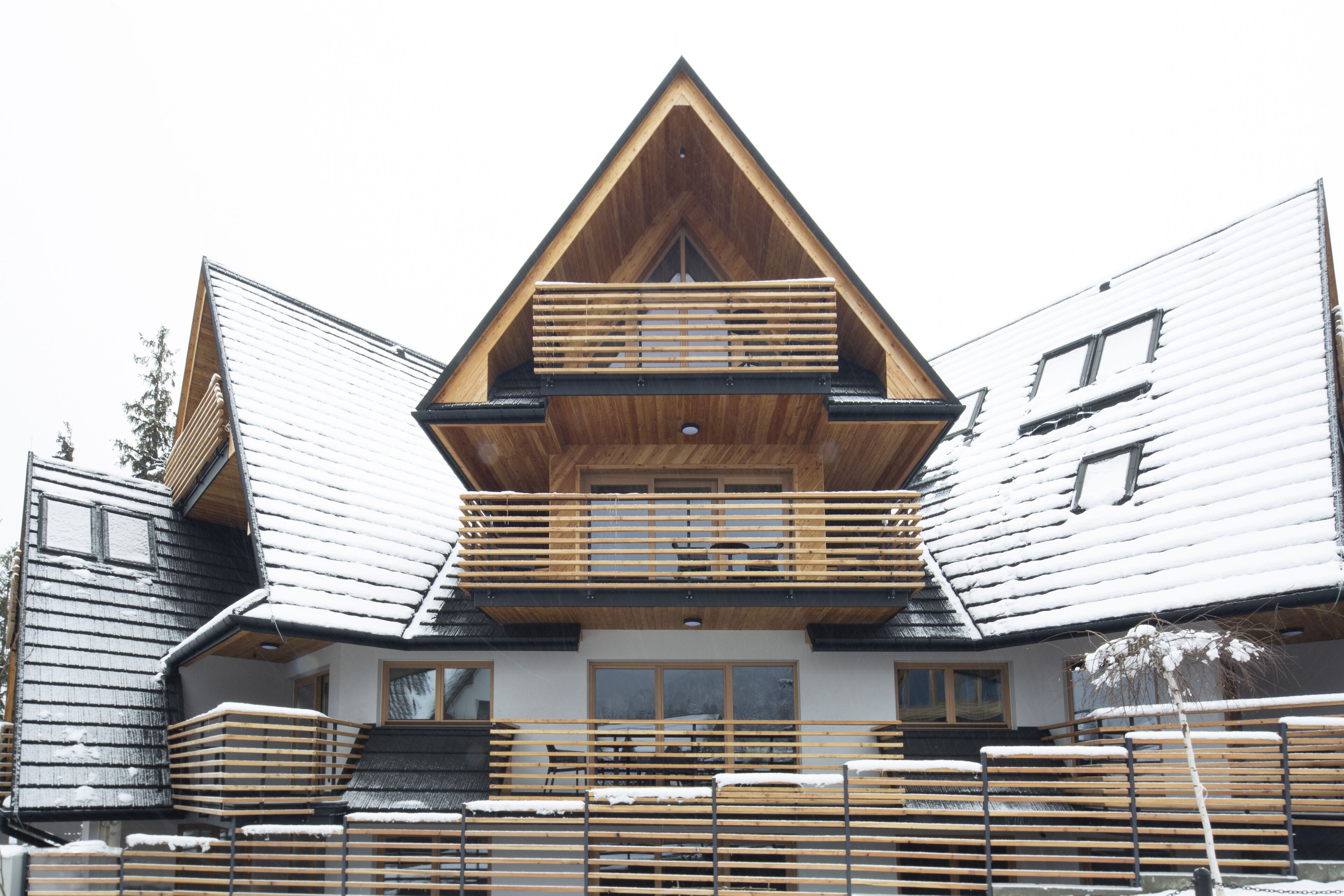 Un chalet doté d’un toit à forte pente, de balcons en bois et d’une façade symétrique.