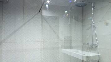 A modern shower with a glass door, a handheld showerhead, and a wall-mounted control panel.