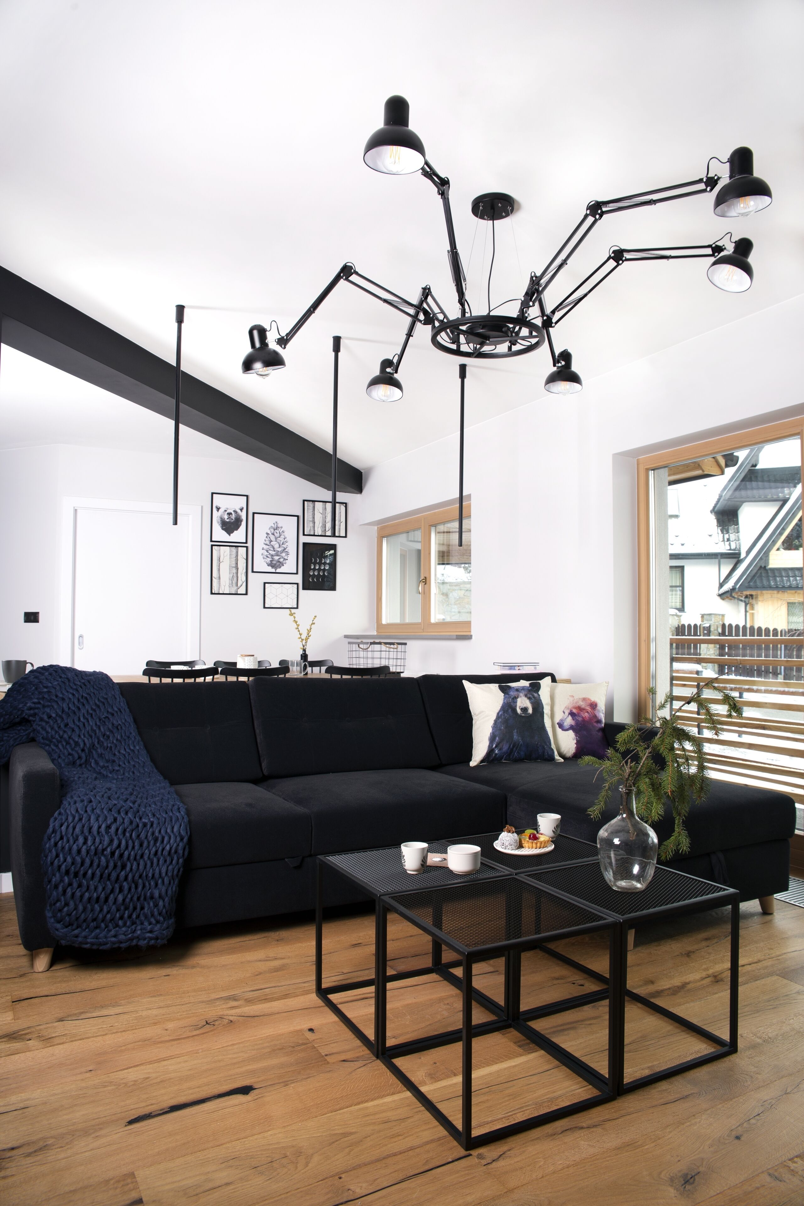 Ein modernes Wohnzimmer mit einem schwarzen Sofa, einem Couchtisch und einer außergewöhnlichen schwarzen Pendelleuchte.
