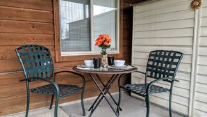 Un petit espace extérieur aménagé avec deux chaises et une table, une fenêtre avec des stores et une porte de garage.