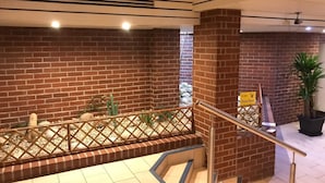 Un escalier avec une rampe en métal, des murs en briques et un panneau jaune avec du texte.