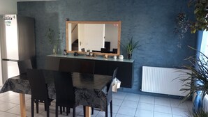 A dining area with a black table and chairs, a refrigerator, a mirror, and potted plants. - EXCLUSIVE House 100 m2 private parking / garden / 6-8 persons (Liévin)
