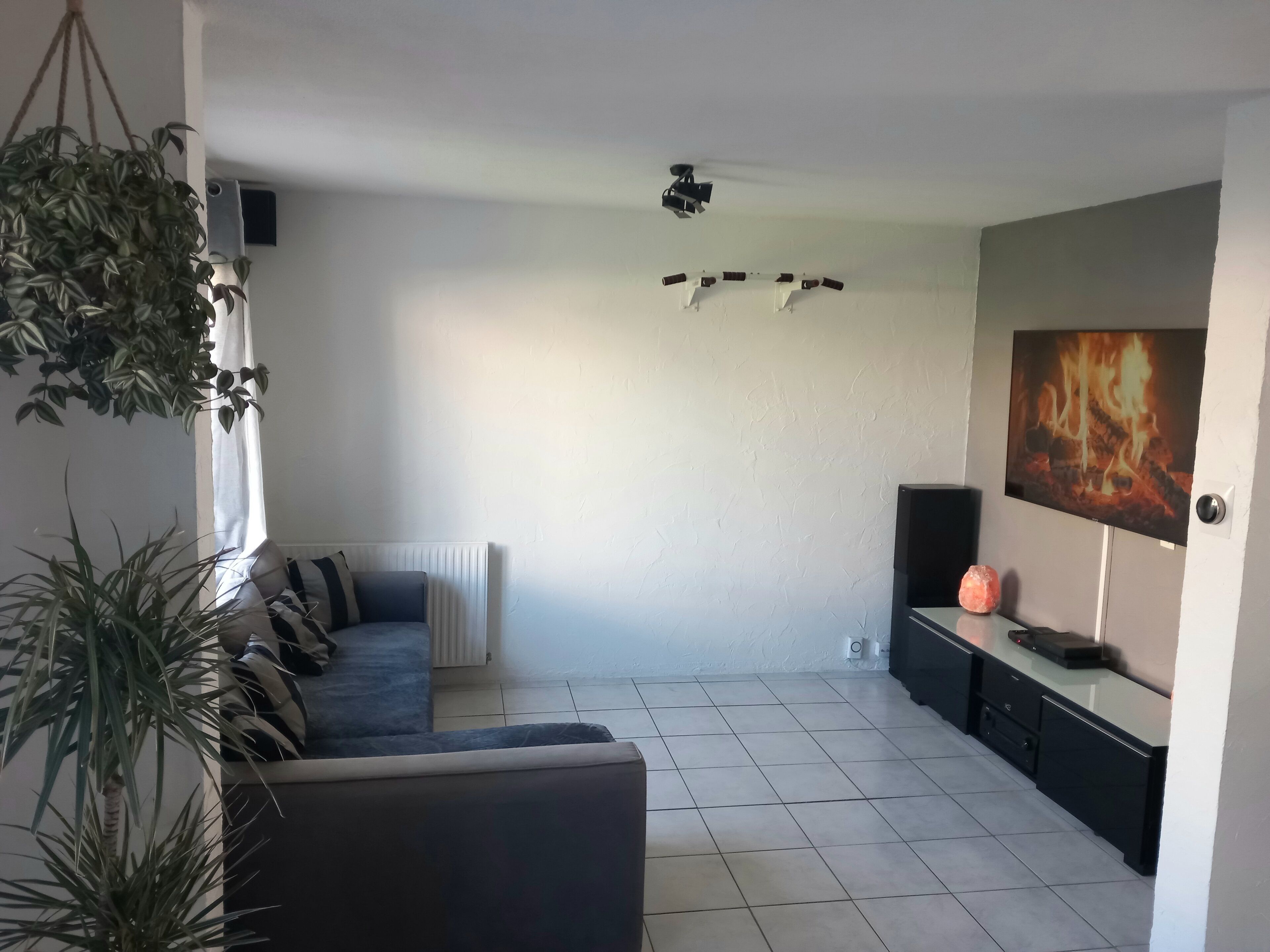 Un salon avec un canapé, un téléviseur, une cheminée et un ventilateur de plafond.