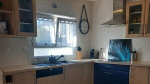 A modern kitchen with wooden cabinets, a stainless steel range hood, and a window with curtains. - EXCLUSIVE House 100 m2 private parking / garden / 6-8 persons (Liévin)