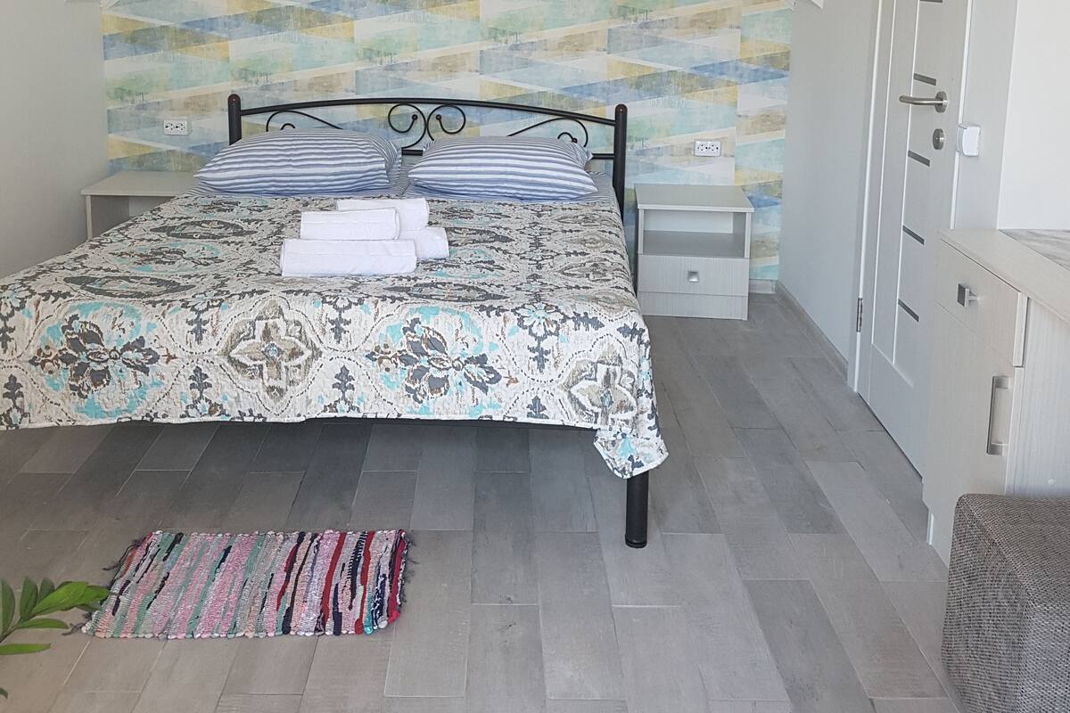 Un dormitorio con cama, mesita de noche, armario y pared con estampado.