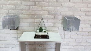 A white brick wall with two metal lanterns on either side of a white shelf holding a small plant and a decorative item. - Apartments like hotel (Chernivtsi)