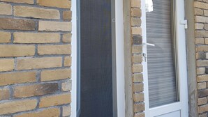 A brick wall with two windows, one with a screen and one with a closed shutter. - Apartments like hotel (Chernivtsi)