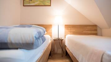A bedroom with two beds, a nightstand with a lamp, and a painting on the wall.
