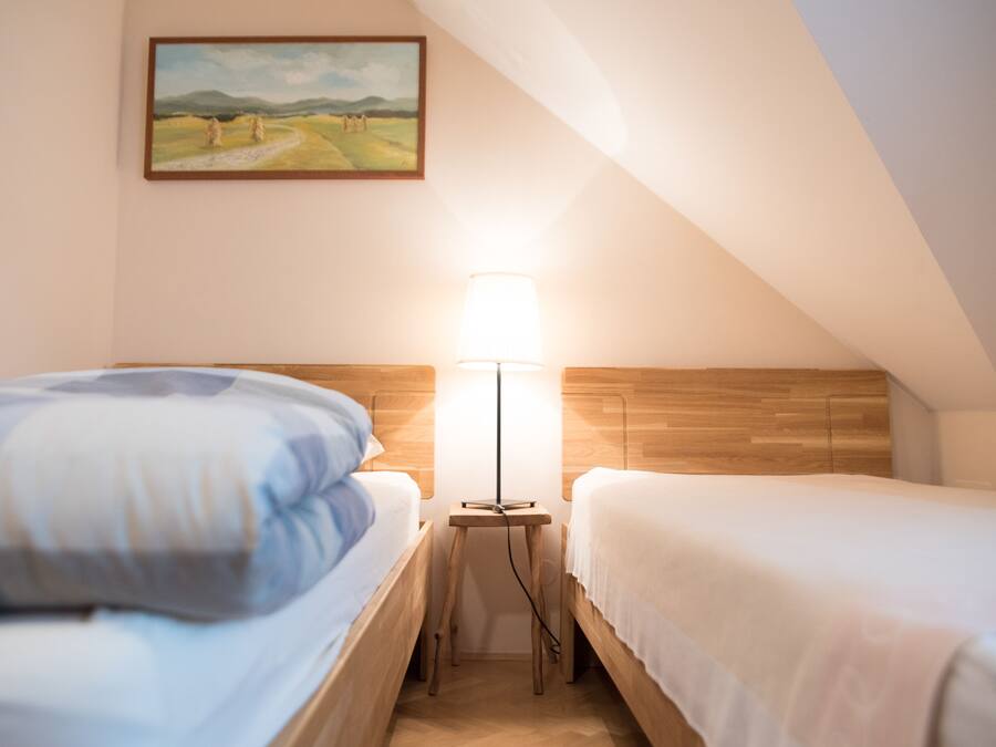 A bedroom with two beds, a nightstand with a lamp, and a painting on the wall.