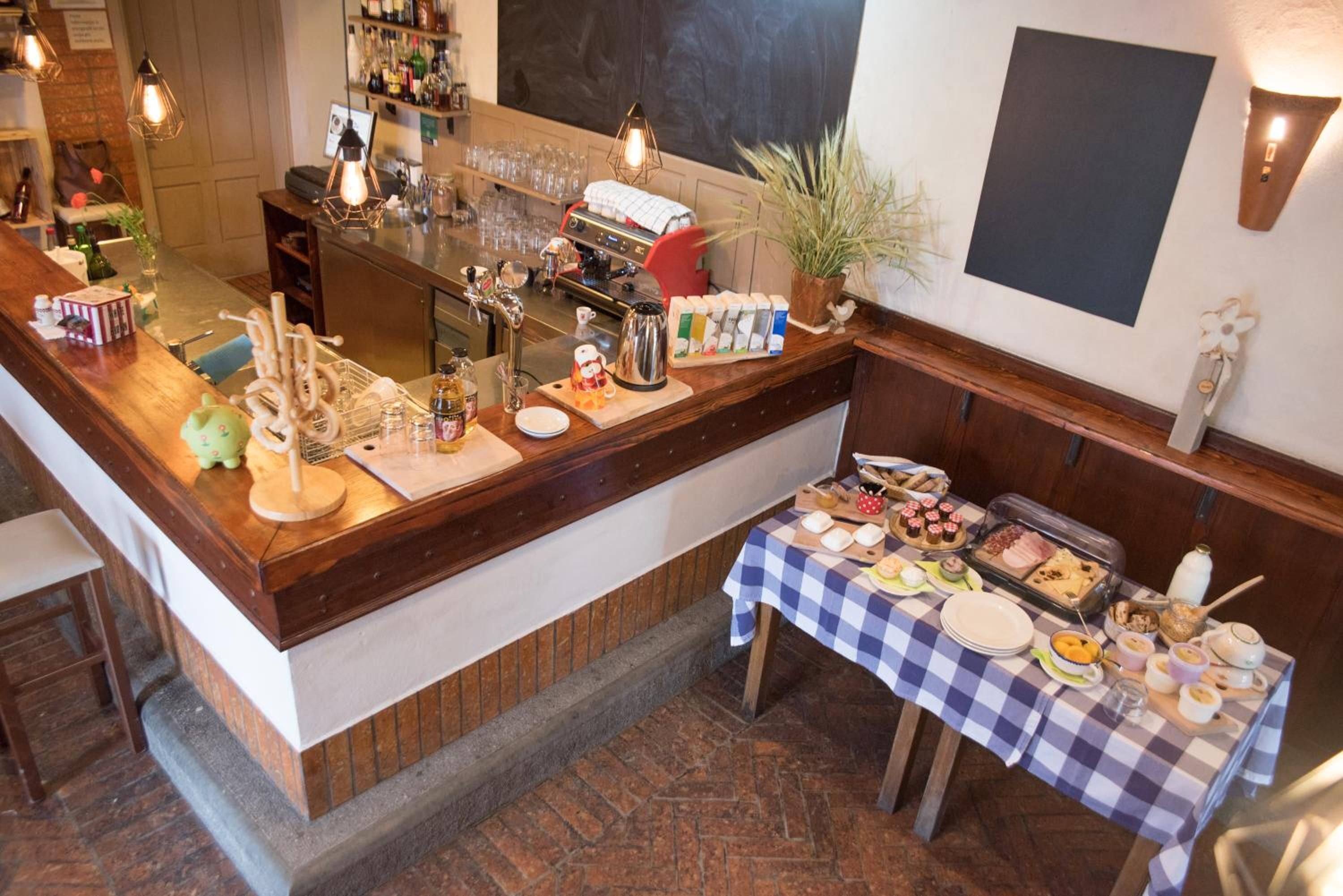 A bar area with a checkered tablecloth, a coffee machine, and various food items on the counter.