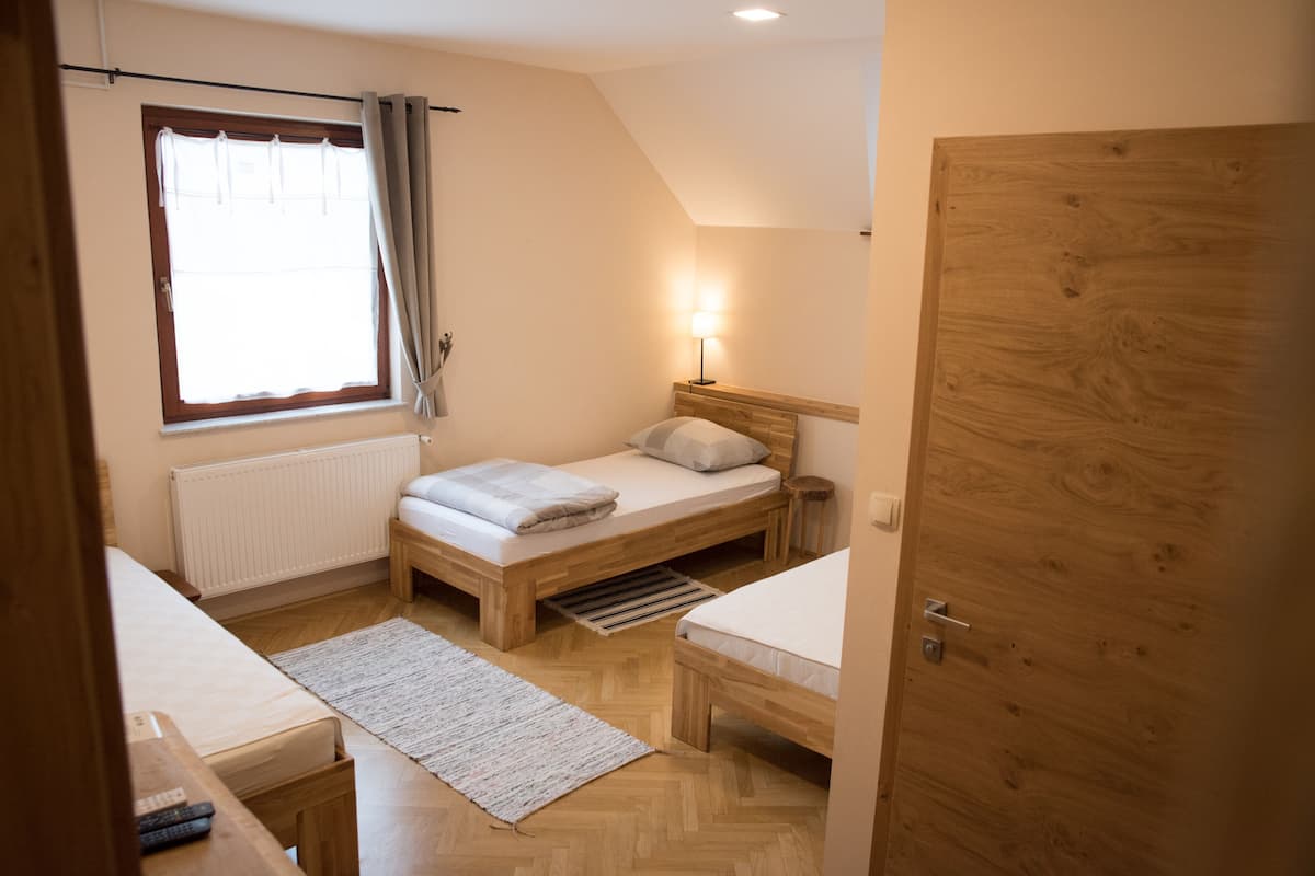 A small, well-lit bedroom with a single bed, a bedside table, a lamp, and a radiator.