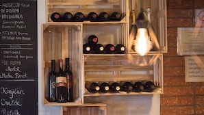A wine rack with multiple bottles and a wooden shelf with more bottles. - Bed & Breakfast Dvorec (Zalec)