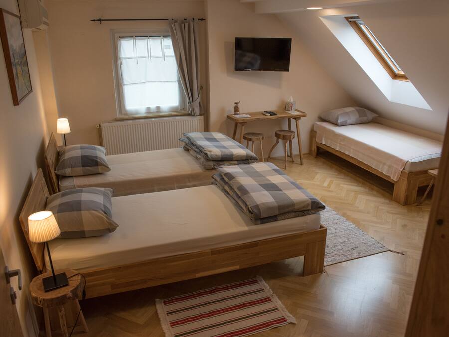 A cozy bedroom with two beds, a desk, a TV, and a window with curtains.