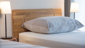 A neatly made bed with a wooden headboard, two bedside lamps, and a bedside table with a lamp. - Bed & Breakfast Dvorec (Zalec)