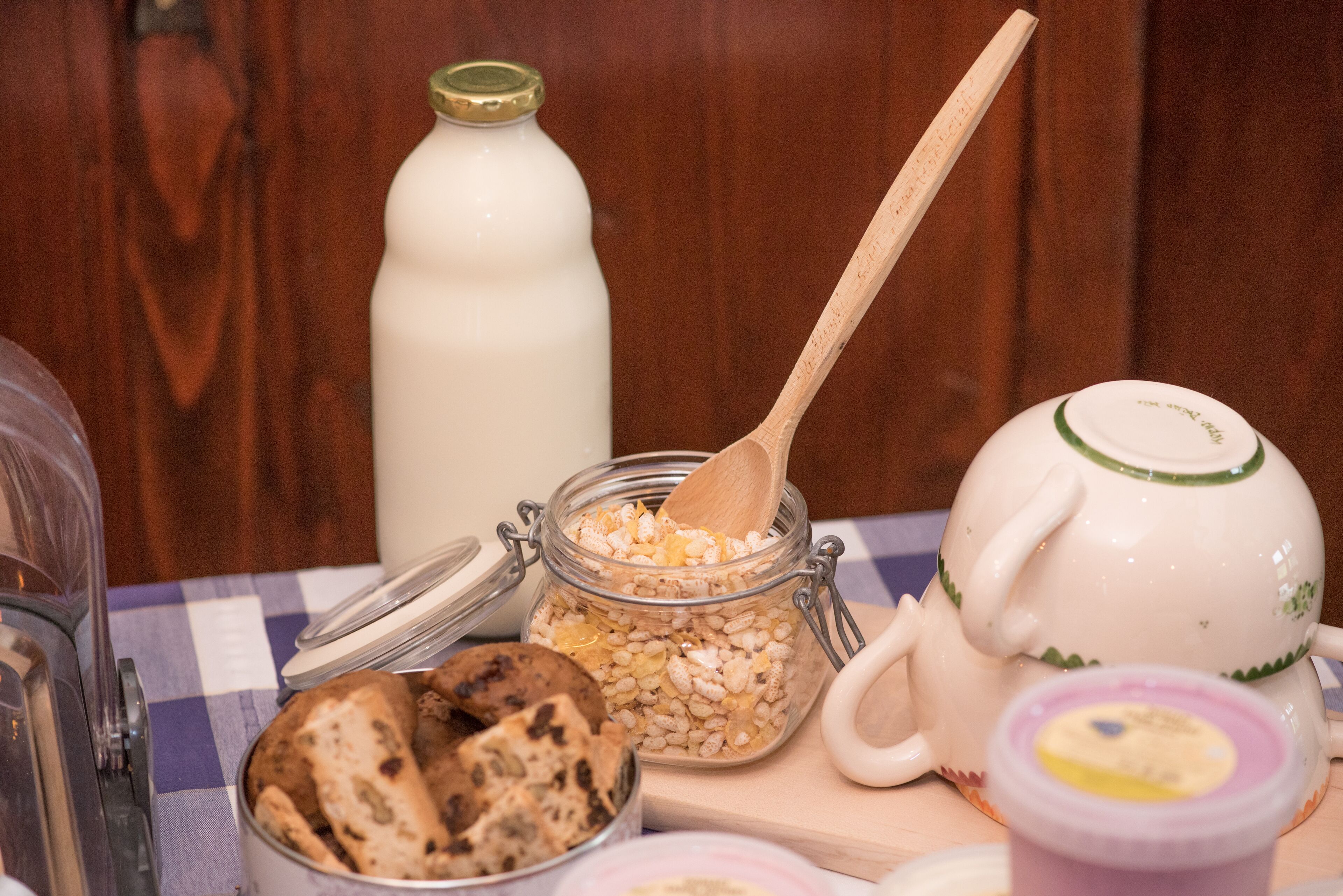 A breakfast setting with a jar of oatmeal, a milk bottle, a teapot, and a plate of cookies.