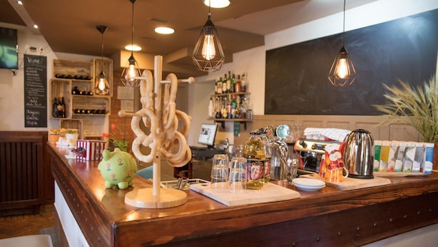 A bar counter with a wooden finish, a piggy bank, and various bottles and glasses. - Bed & Breakfast Dvorec (Zalec)