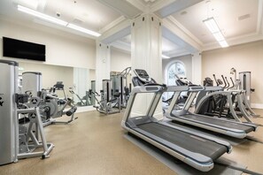Un gimnasio con cintas de correr, máquinas de pesas y un espejo grande.