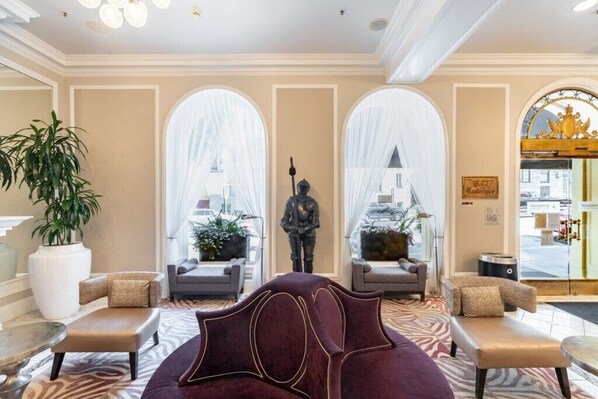 Un hall d'hôtel doté d'un coin salon confortable, de grandes fenêtres et d'une statue.