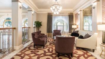 A spacious living room with a patterned carpet, a chandelier, and a white sofa.
