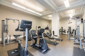 Un gimnasio con diferentes equipos de ejercicio, incluyendo cintas de correr, bicicletas estáticas y máquinas de pesas.