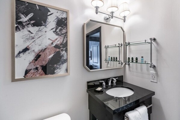 A modern bathroom with a large mirror, a black countertop sink, and a towel rack.