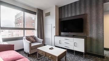 Habitación de hotel con una ventana grande, televisor de pantalla plana, sofá, mesa de centro y un armario.