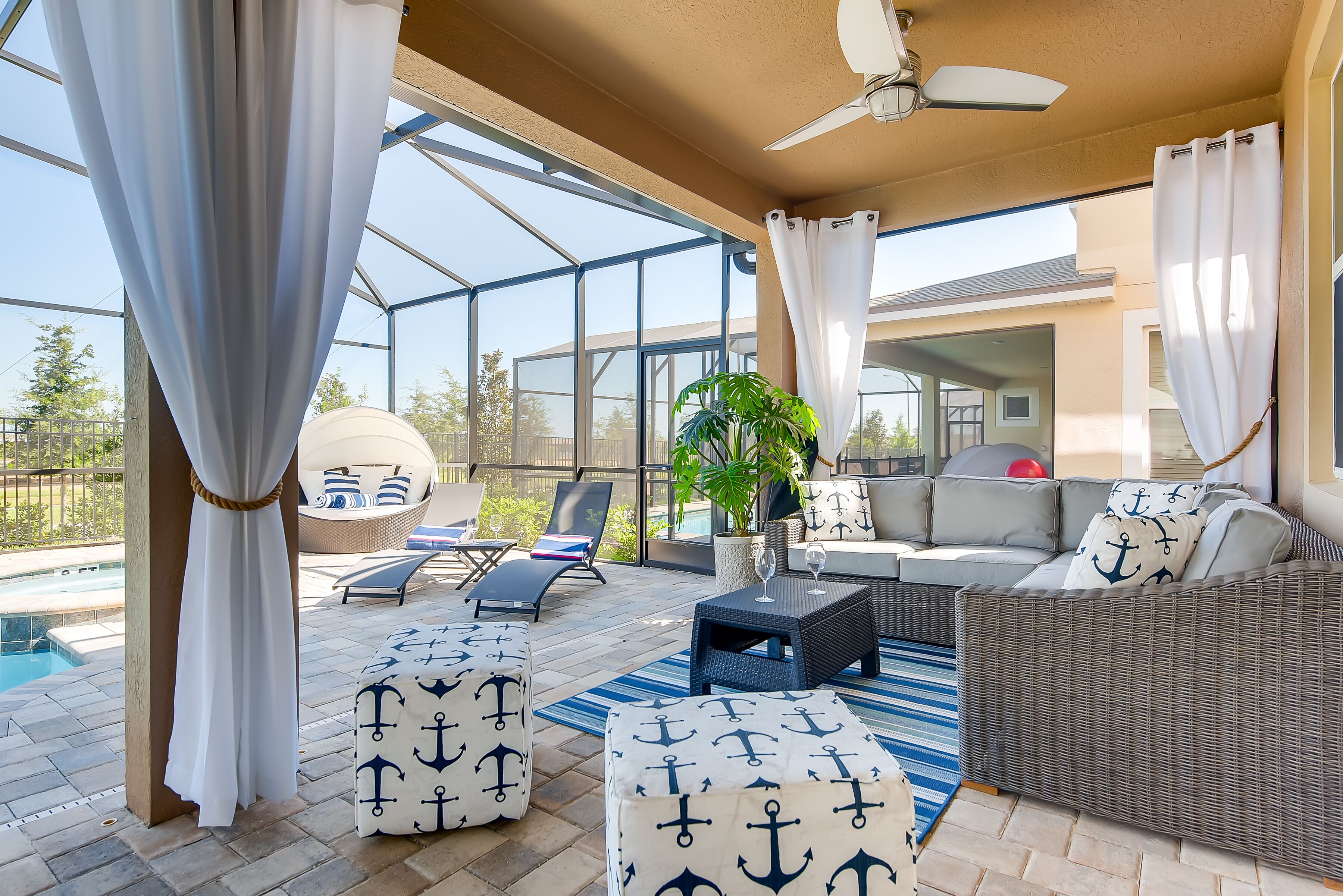Eine sonnige Terrasse mit Pool, Sitzmöbeln und Deckenventilator.