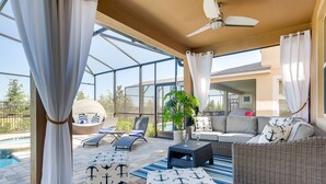 A sunlit patio with a pool, outdoor seating, and a ceiling fan. - 5 STAR Luxury Home, Indoor Playground, Baby Friendly, Solara Resort, Near Disney (Kissimmee)