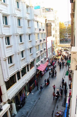 A bustling street scene with a row of white buildings, shops, and pedestrians.