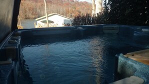 A hot tub with a view of a house and trees.