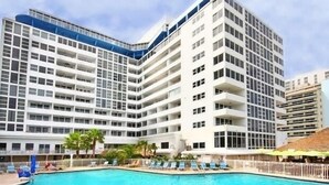 A modern hotel with multiple floors, a swimming pool, and outdoor seating areas. - Beach Front Building sits on the sand/ocean<br>  Newly  remodeled  beautiful condo<br> (Fort Lauderdale)