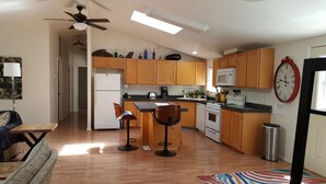 A modern kitchen with wooden cabinets, a gas stove, a microwave, and a refrigerator. There are two bar stools and a coffee maker on the counter. - Explore Amador & Calaveras Counties. Kirkwood 45 minutes away. (West Point)