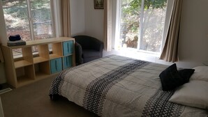 A bedroom with a bed, a desk with storage, a chair, and large windows. - Explore Amador & Calaveras Counties. Kirkwood 45 minutes away. (West Point)