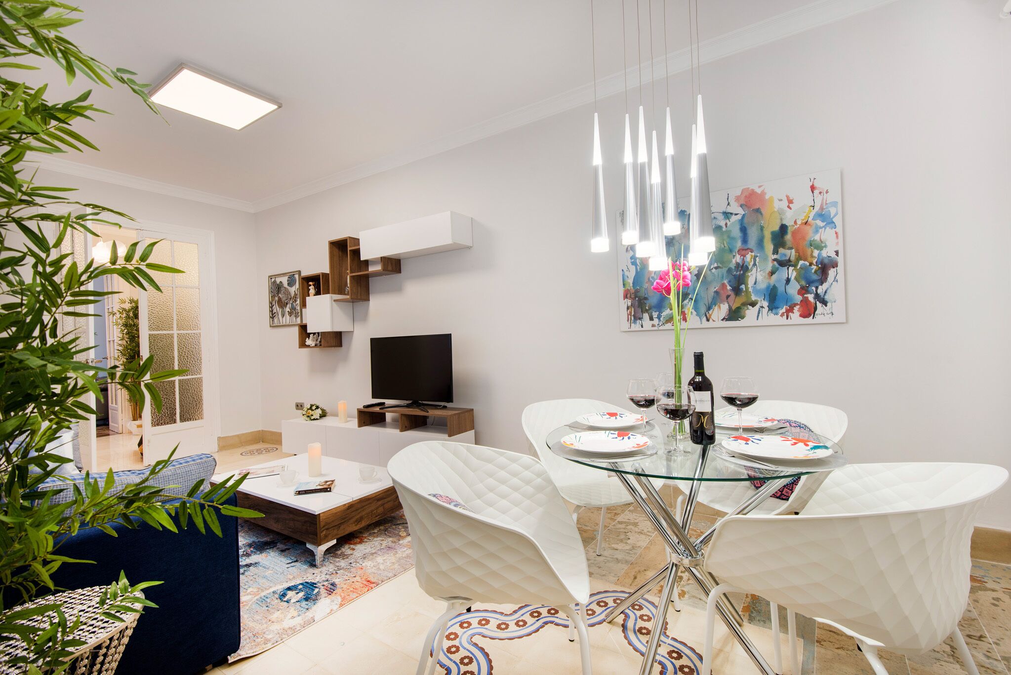 Een moderne eetruimte met een glazen tafel, witte stoelen en een schilderij aan de muur.