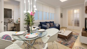 Een moderne woonkamer met een glazen eettafel, een bank en een televisie.