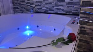 Un jacuzzi con una decoración de rosas, un panel de control y una pared texturizada al fondo.